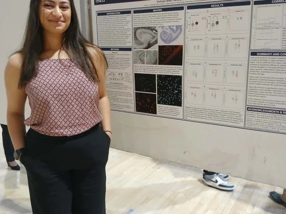 Undergraduate student standing next to their Poster Session Board