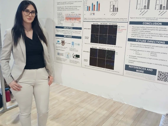 Undergraduate student standing next to their Poster Session Board