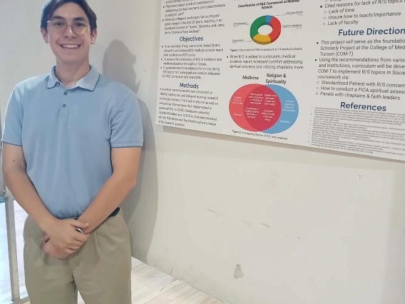 Undergraduate student standing next to their Poster Session Board