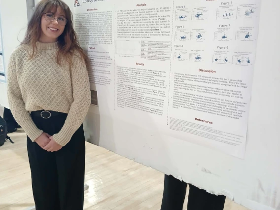 Undergraduate student standing next to their Poster Session Board
