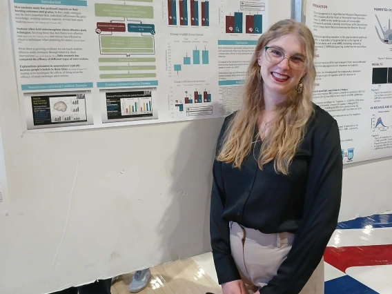 Undergraduate student standing next to their Poster Session Board
