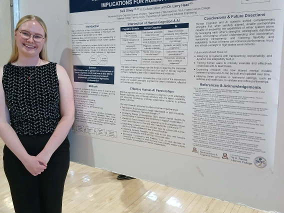 Undergraduate student standing next to their Poster Session Board