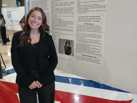 Undergraduate student standing next to their Poster Session Board