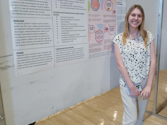 Undergraduate student standing next to their Poster Session Board