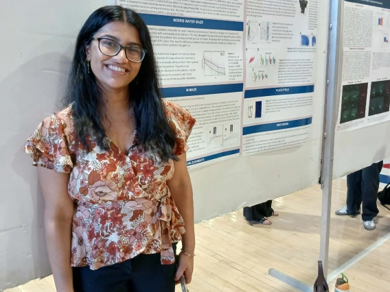 Undergraduate student standing next to their Poster Session Board