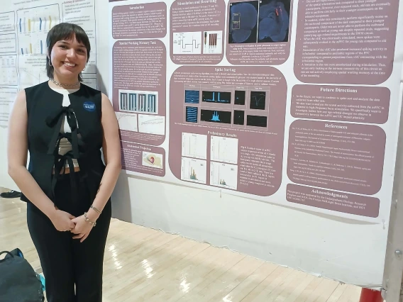 Undergraduate student standing next to their Poster Session Board