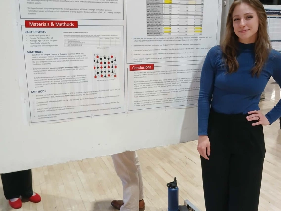 Undergraduate student standing next to their Poster Session Board