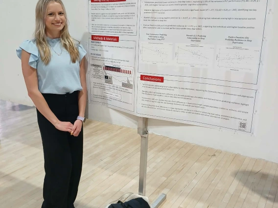 Undergraduate student standing next to their Poster Session Board