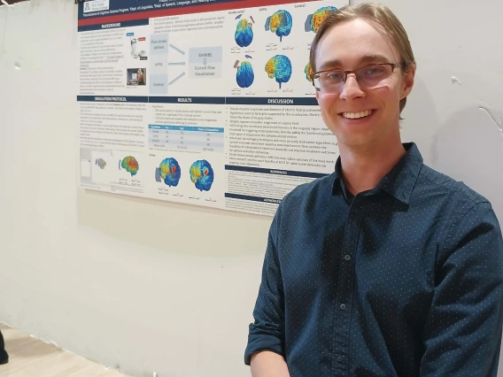 Undergraduate student standing next to their Poster Session Board