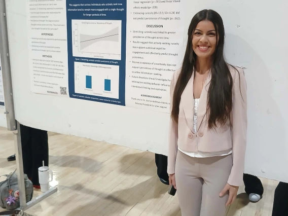 Undergraduate student standing next to their Poster Session Board