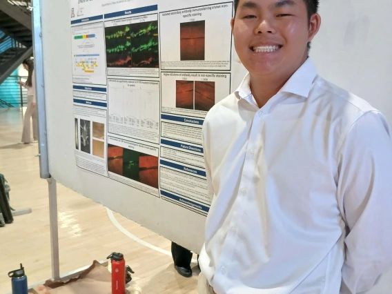 Undergraduate student standing next to their Poster Session Board