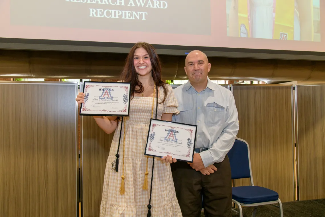 Cecilia Roessle standing with Dr. Ricoy, displaying Outstanding Senior Award and Diploma.