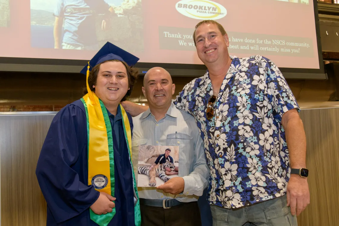 NSCS graduate with Drs. Nighorn and Ricoy after winning infamous photo of Dr. Nighorn with tiger.